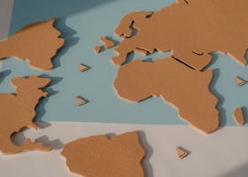 Stylized cork world map on blue paper with shadows, highlighting continents.