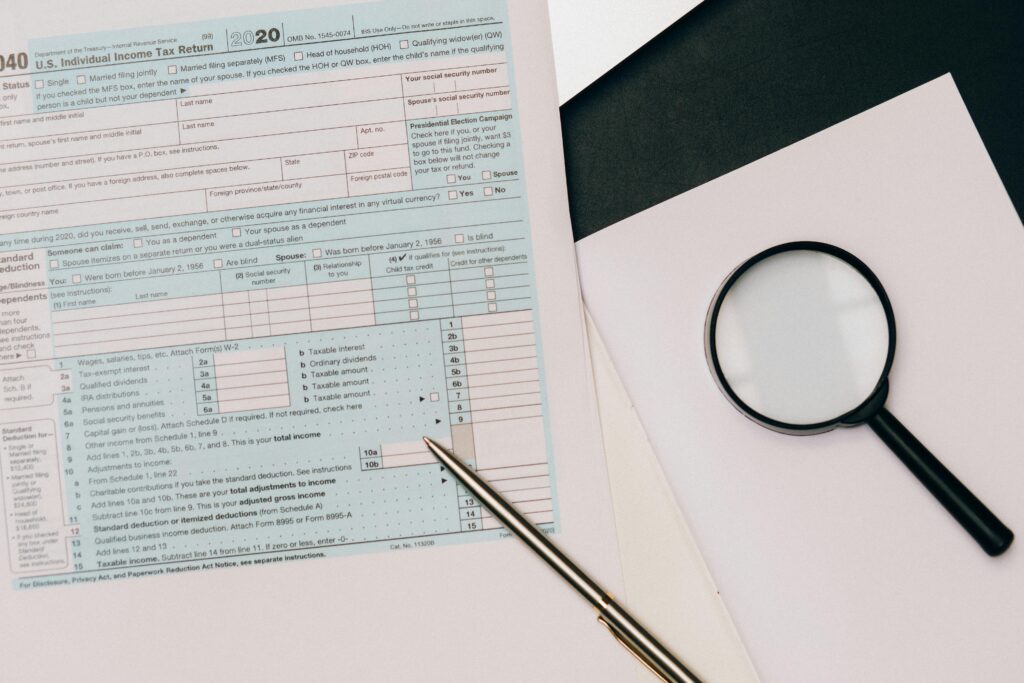 A detailed view of a tax return form with a pen and magnifying glass, perfect for financial themes.